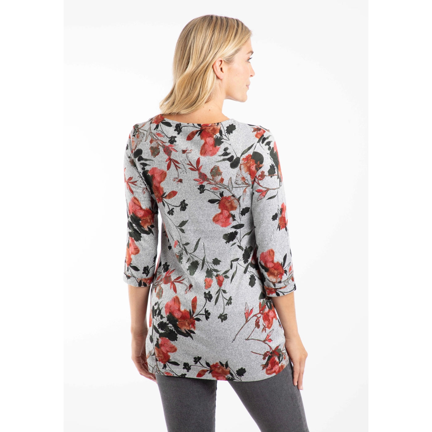 Back view of a woman wearing a Weird Fish Sidney floral 3/4 sleeve tunic in grey with a red and green floral print on a white background