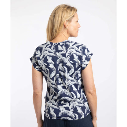 Back view of a woman wearing a short sleeve Weird Fish Alia t-shirt in Ink blue with an ecru palm tree leaf print on a white background