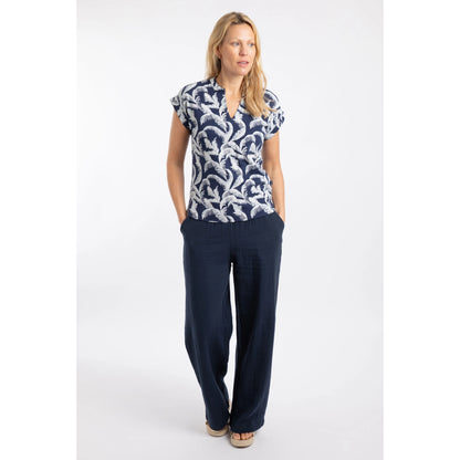Woman wearing a Weird Fish short sleeve Alia t-shirt in ink blue with an ecru palm tree leaf print and dark trousers on a white background