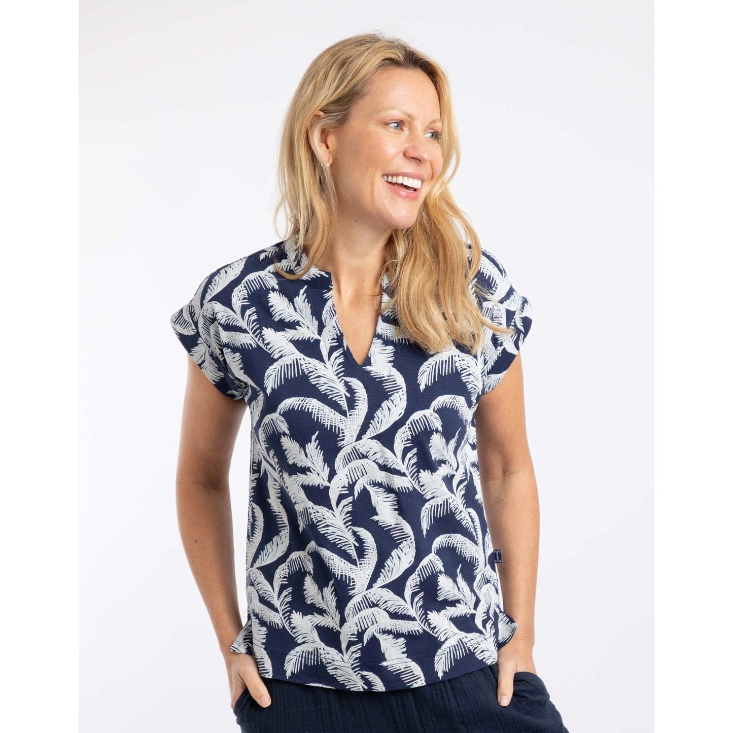 Front view of a woman wearing a Weird Fish short sleeve Alia t-shirt in Ink blue with an ecru palm leaf pattern on a white background