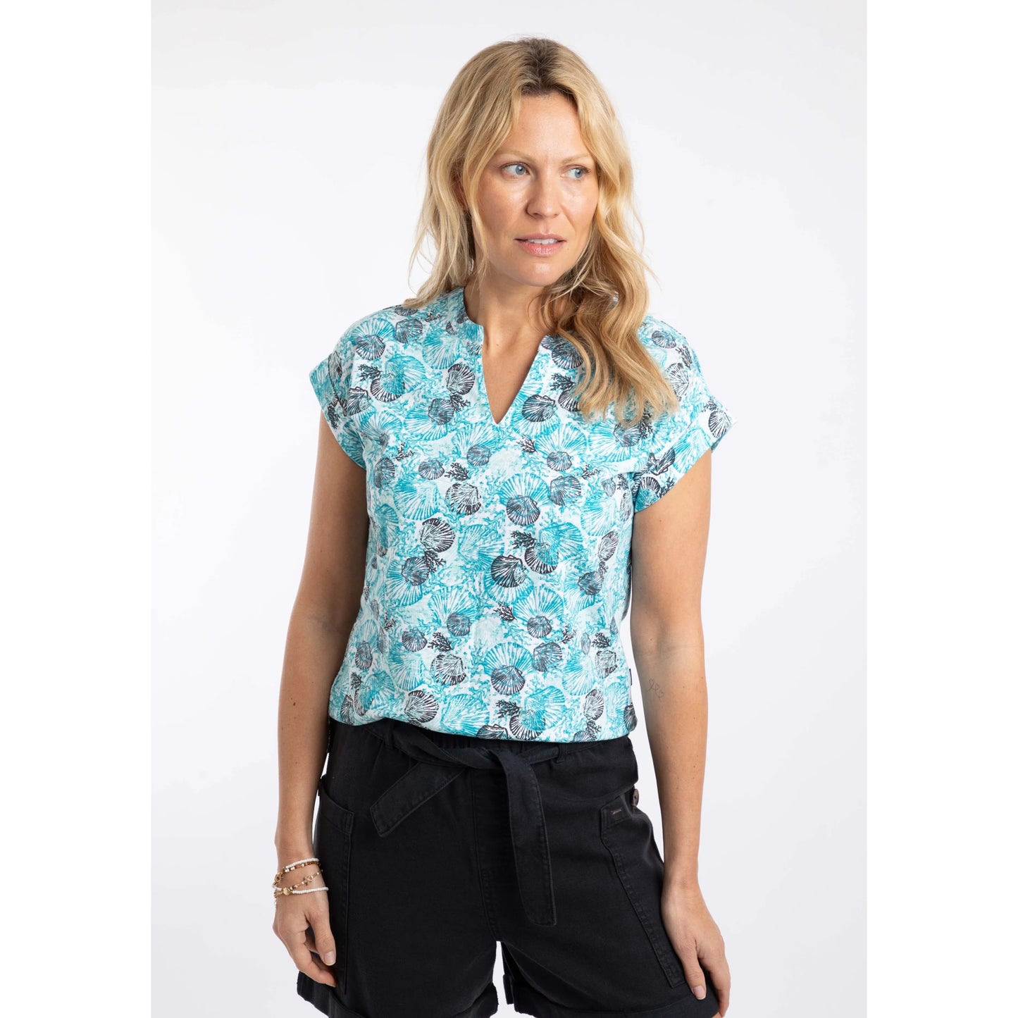 Front view of a woman wearing a Weird Fish short sleeve Alia Ocean Blue shell print t-shirt with black shorts on a white background