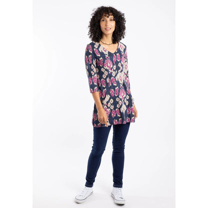 Woman wearing a petrol blue, pink and purple abstract pattern Weird Fish Arielle tunic with blue jeans on a white background