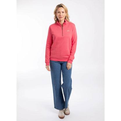 Woman wearing a Weird Fish Avery 1/4 zip plain sweatshirt in Flamingo Pink with blue jeans and beige trainers