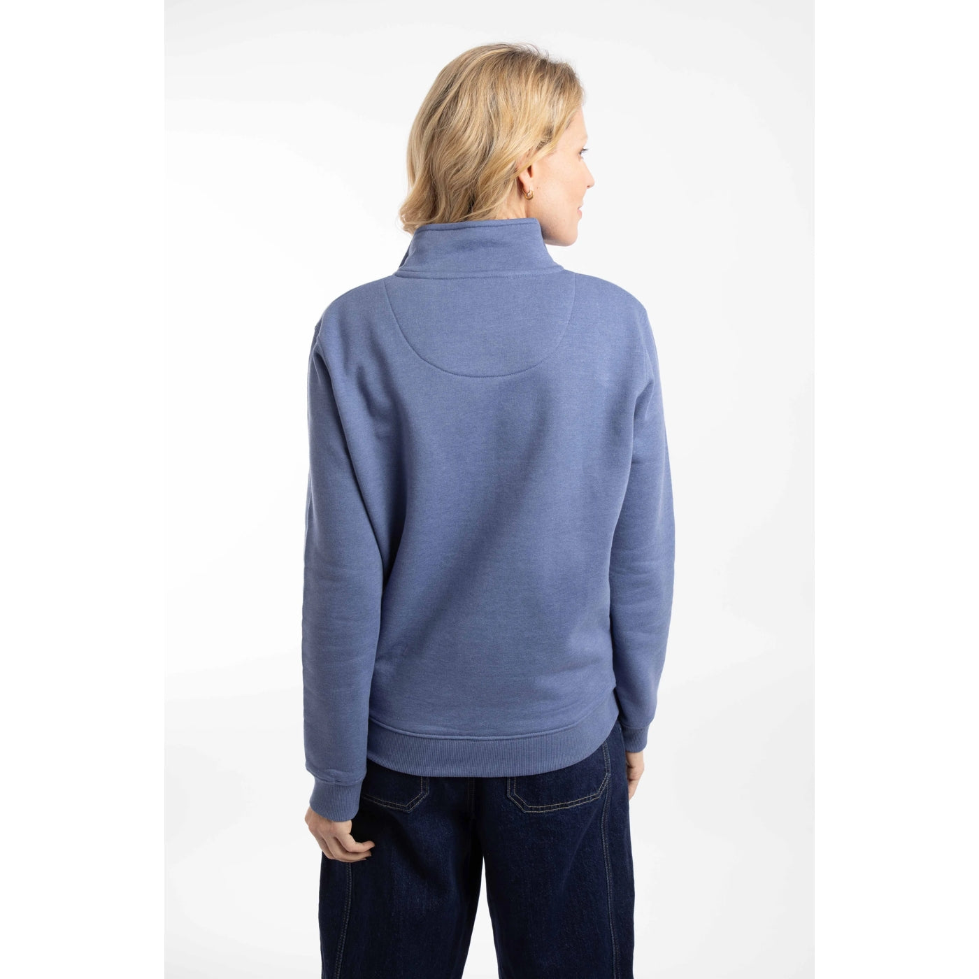 Back view of a woman wearing a Weird Fish Avery 1/4 zip plain sweatshirt in Faded Blue with elasticated cuffs and bottom hem