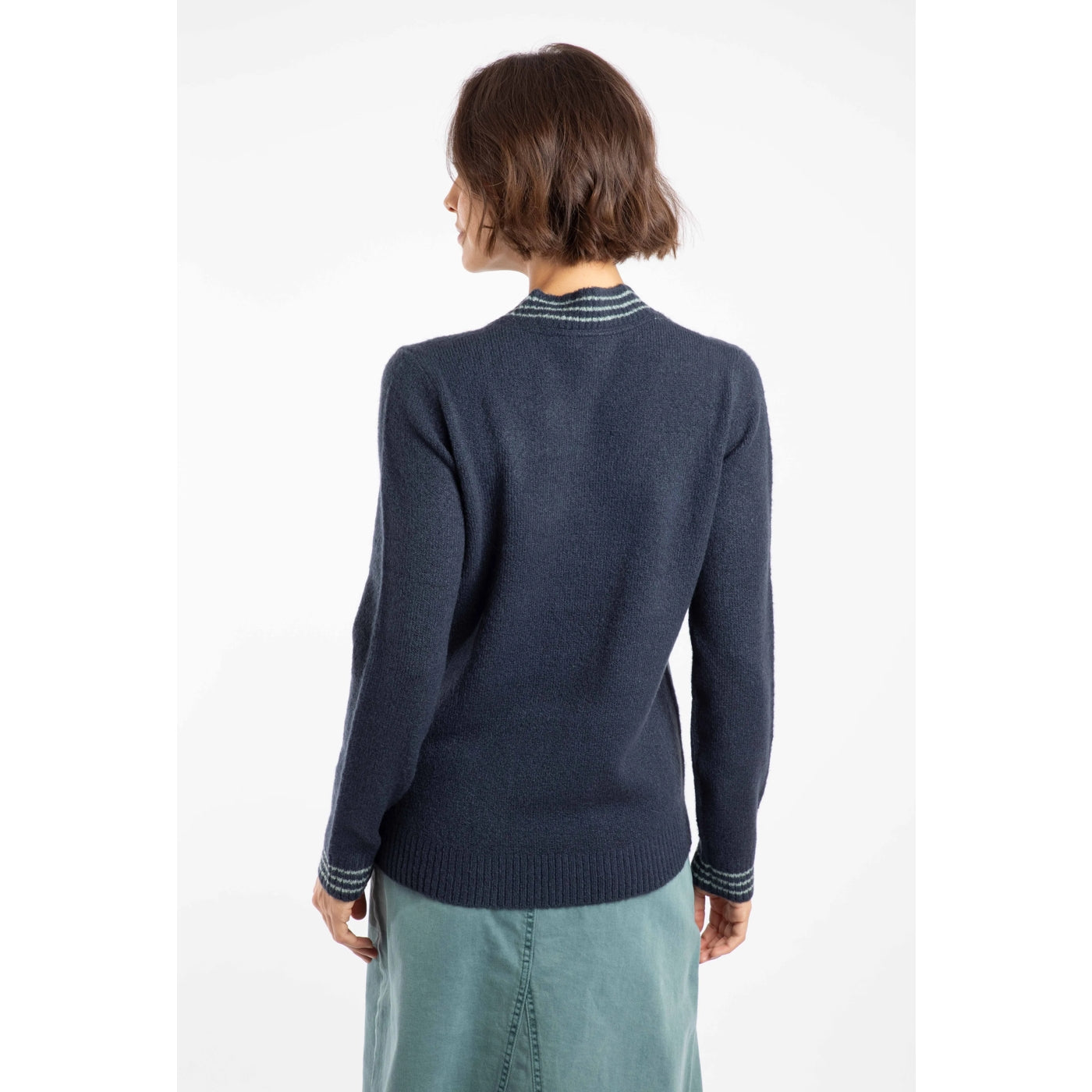 Back view of a woman wearing a navy Weird Fish knitted Dawkins jumper with striped cuffs on a white background