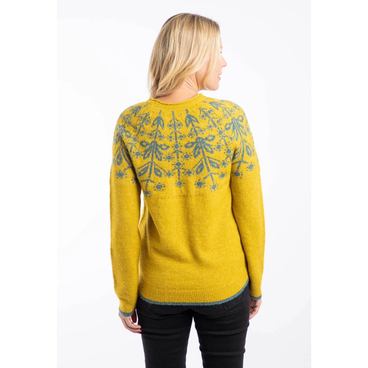 Back view of a woman wearing a Weird Fish yellow Miska jumper with a green Fair Isle pattern and beige trousers.