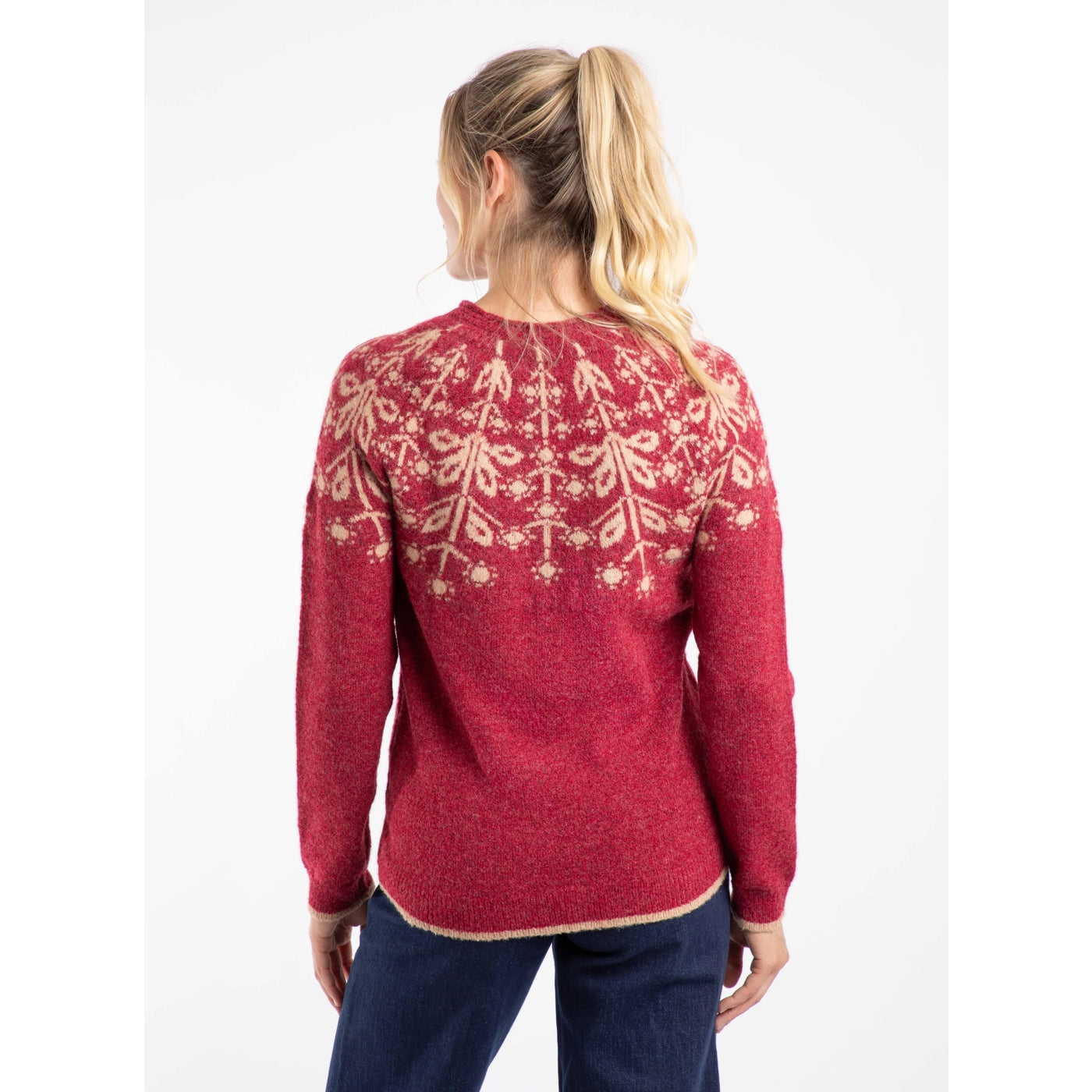 Back view of a woman wearing a Weird Fish red Miska jumper with a beige Fair Isle pattern and navy blue trousers.