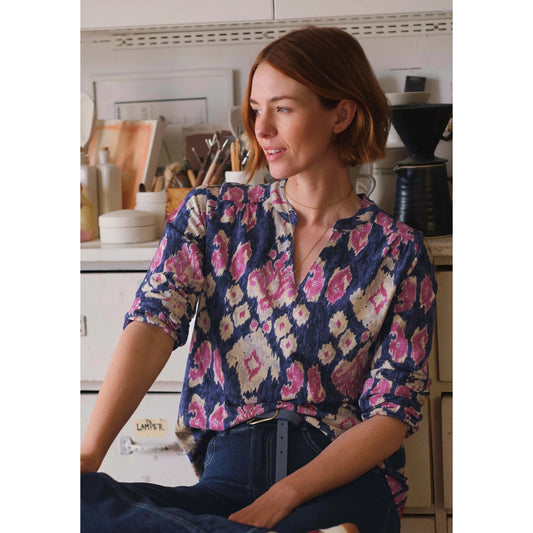 Woman wearing a Weird Fish Brooke  blouse with a blue and pink-purple abstract pattern in a kitchen setting