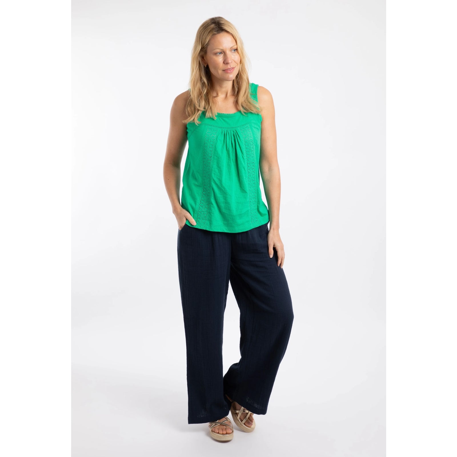 Woman wearing a Weird Fish Chelle square neck vest in Gumdrop Green with navy trousers.