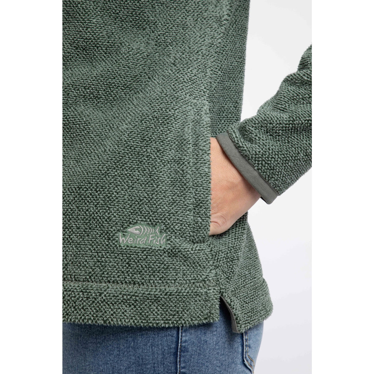 Close-up view of the tummy pocket and logo on a Weird Fish womens 1/4 zip Sarah fleece in Military Green.