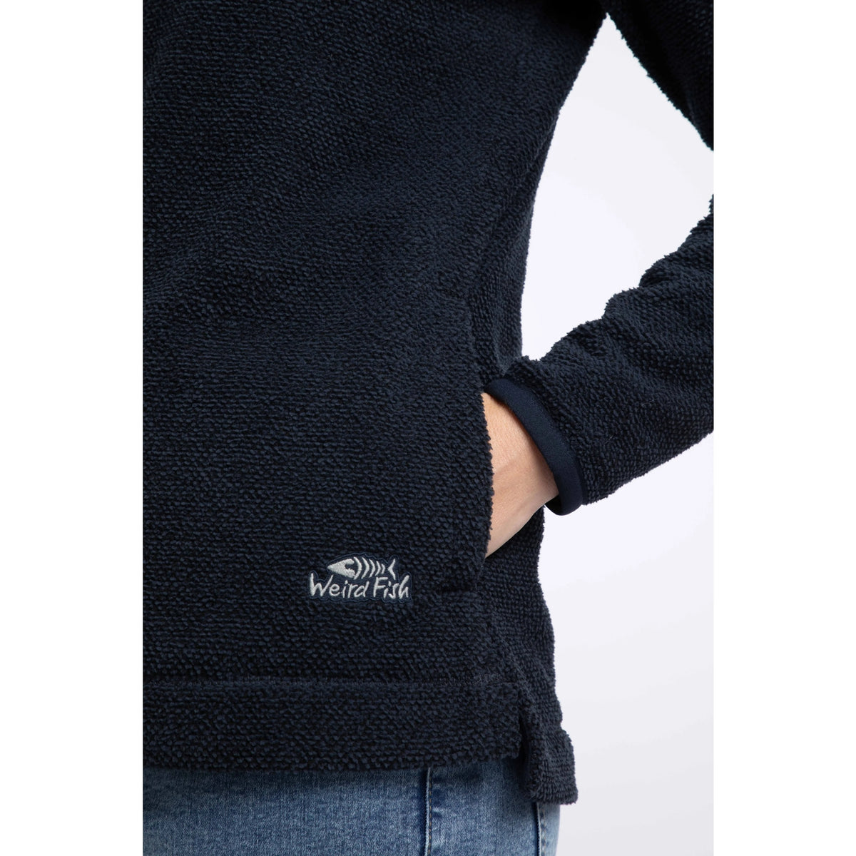 Close-up view of the tummy pocket and logo on a Weird Fish womens 1/4 zip Sarah fleece in Midnight Navy