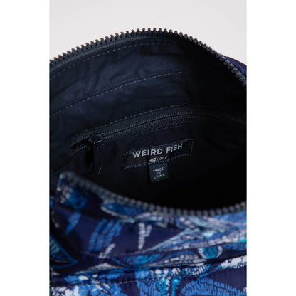 Close-up view of the internal pocket of a Weird Fish Kait cross body bag in navy with an indigo blue tropical leaf print.