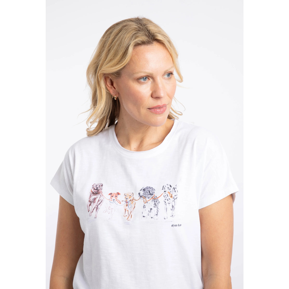 Close-up view of a woman wearing a Weird Fish short sleeve Take the Lead t-shirt in white with five dogs printed across the chest.