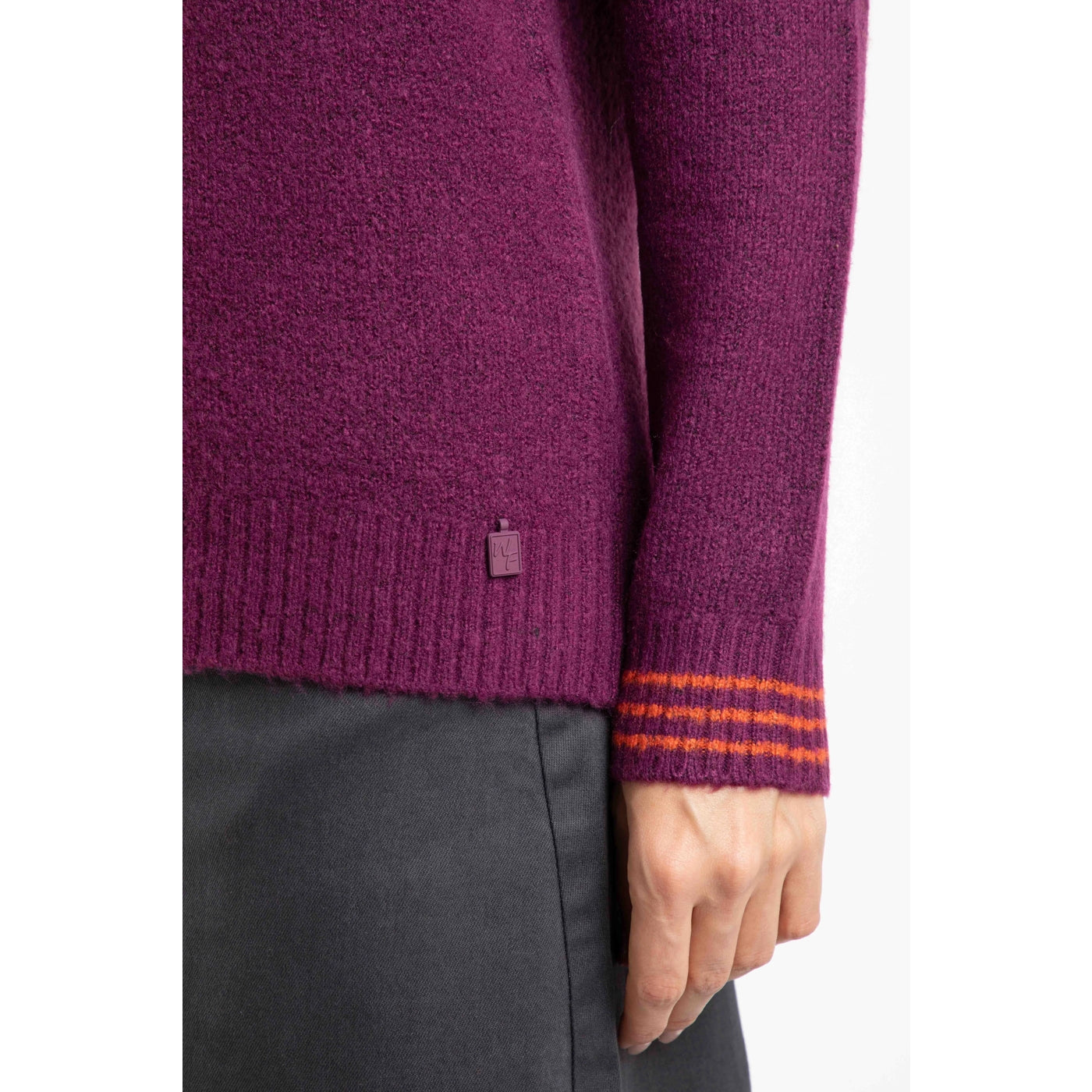 Close-up of a Weird Fish womens Dawkins jumper stripe cuff in Beet Purple with a brand logo on a white background
