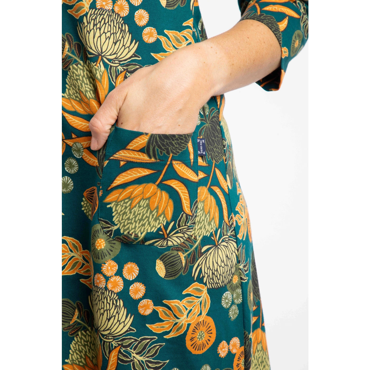 Weird Fish Starshine Deep Teal floral patterned dress with a hand in the pocket on a white background