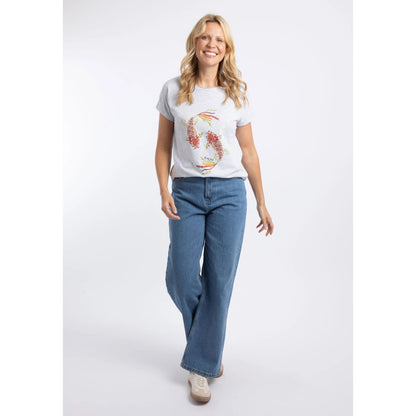 A woman wearing a Weird Fish short sleeve t-shirt in Light Grey Marl with a Koi Carp print on the front made up of Fern leaves, with blue jeans and white trainers.