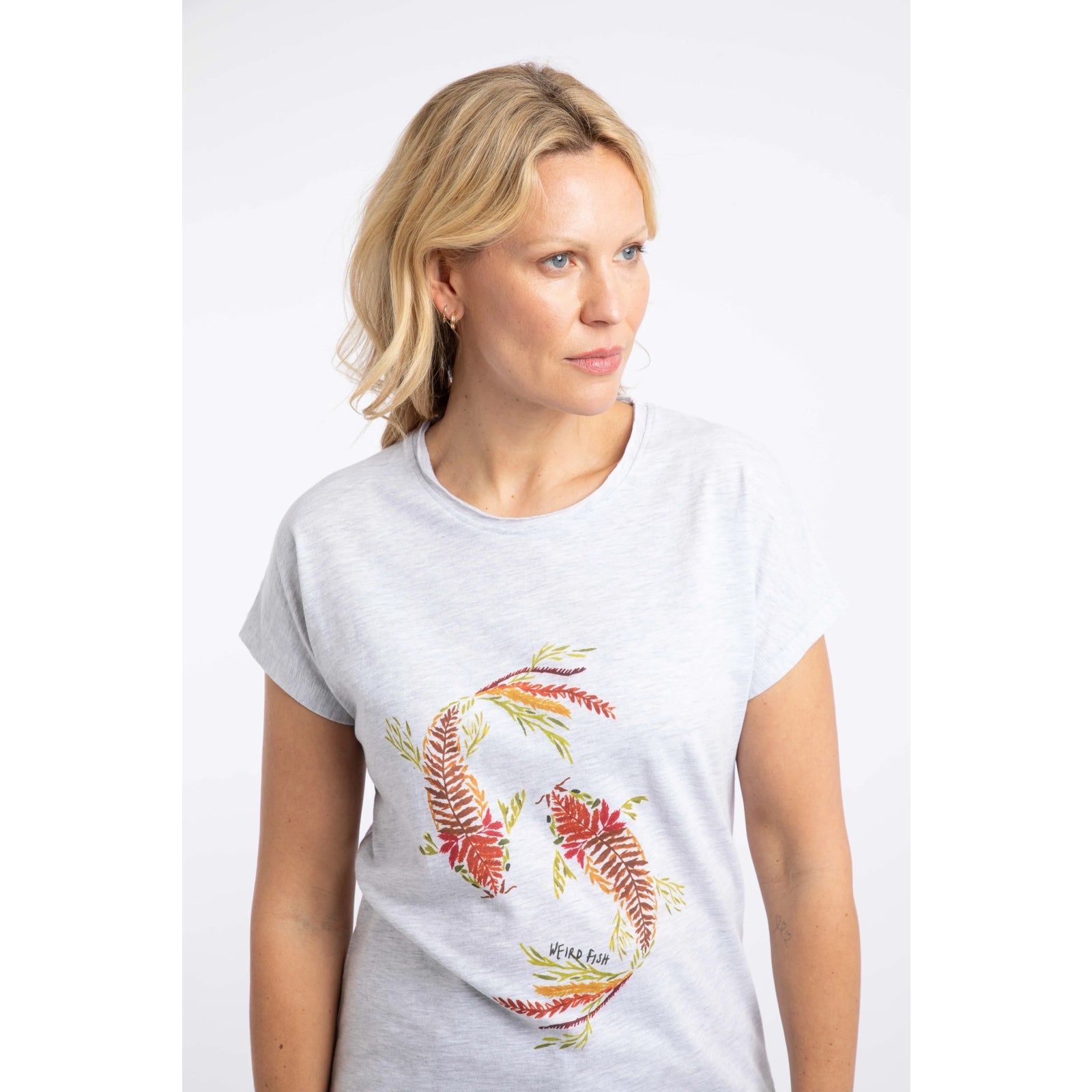 Close-up view of a woman wearing a Weird Fish short sleeve t-shirt in Light Grey Marl with a Koi Carp print on the front made up of Fern leaves.