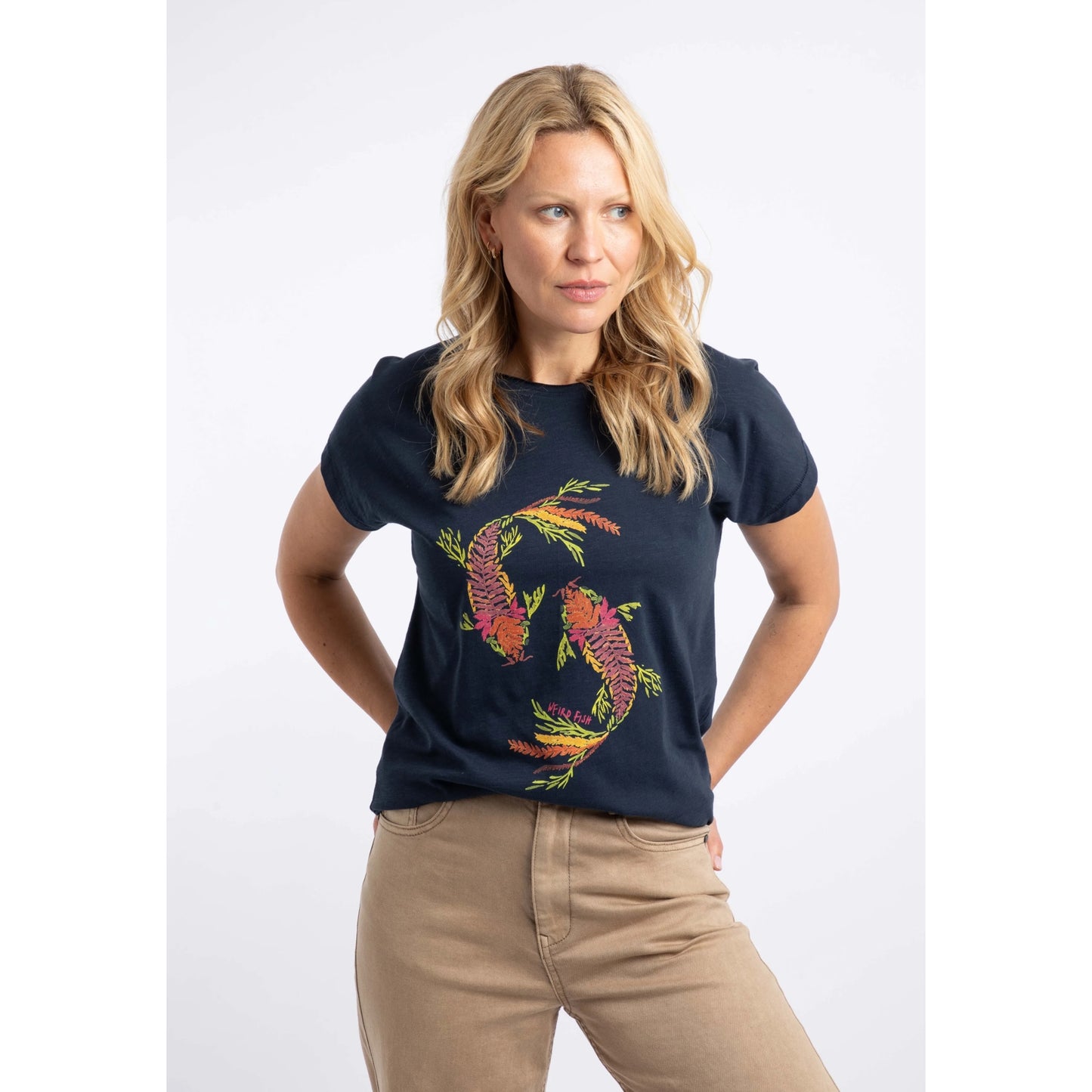 Front view of a woman wearing a Weird Fish short sleeve navy t-shirt featuring an abstract koi carp print made up of fern leaves on the front.