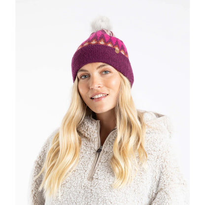 Woman wearing a beet purple Weird Fish Frady knitted beanie with a Fair Isle pattern and a faux fur pom-pom on a white background