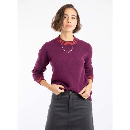 Woman wearing a Weird Fish Dawkins beet purple knitted jumper with red trim on a white background