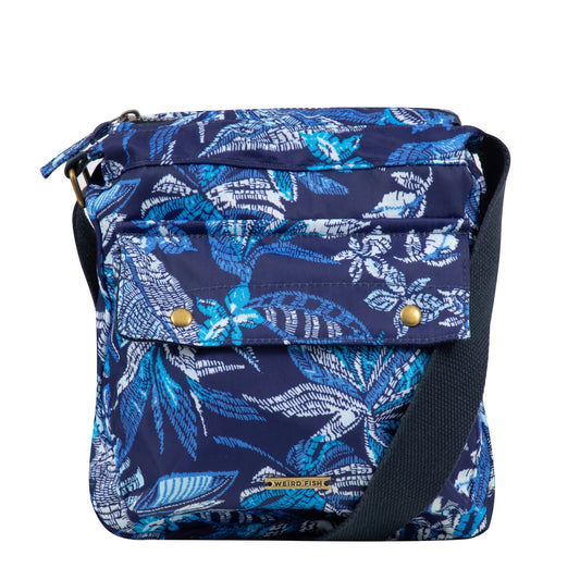 Front view of a Weird Fish Kait cross body bag in navy with a blue tropical leaf print, adjustable shoulder strap and front pocket.