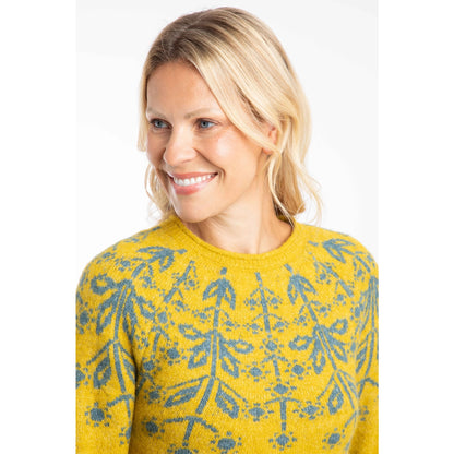 Woman wearing a Weird Fish yellow Miska jumper with a green Fair Isle pattern across the chest and shoulders.