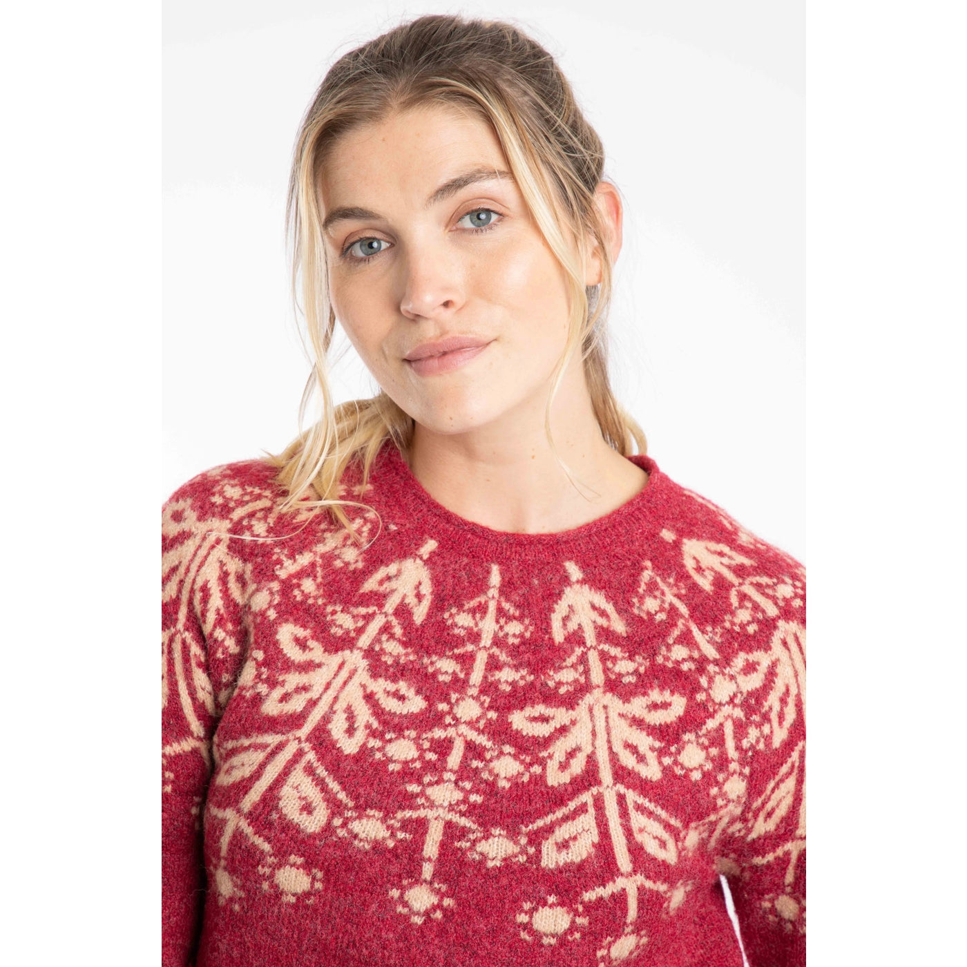 Woman wearing a Weird Fish red Miska jumper with a beige Fair Isle pattern across the chest and shoulders.