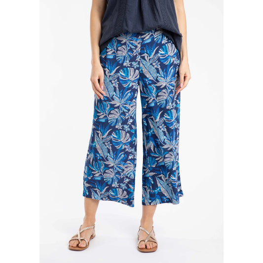 Front view of a woman wearing a pair of Weird Fish Sarita wide leg crinkle viscose cropped trousers in indigo blue with a tropical leaf pattern.