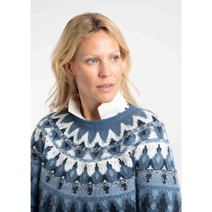 Close-up view of a woman wearing a Weird Fish knitted Lowell jumper in Ash Blue, with a Fair Isle pattern across the chest and shoulders.