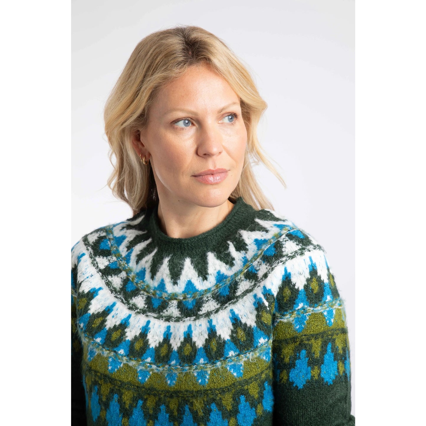 Close-up view of a woman wearing a Weird Fish knitted Lowell jumper in Bottle Green, with a Fair Isle pattern across the chest and shoulders.