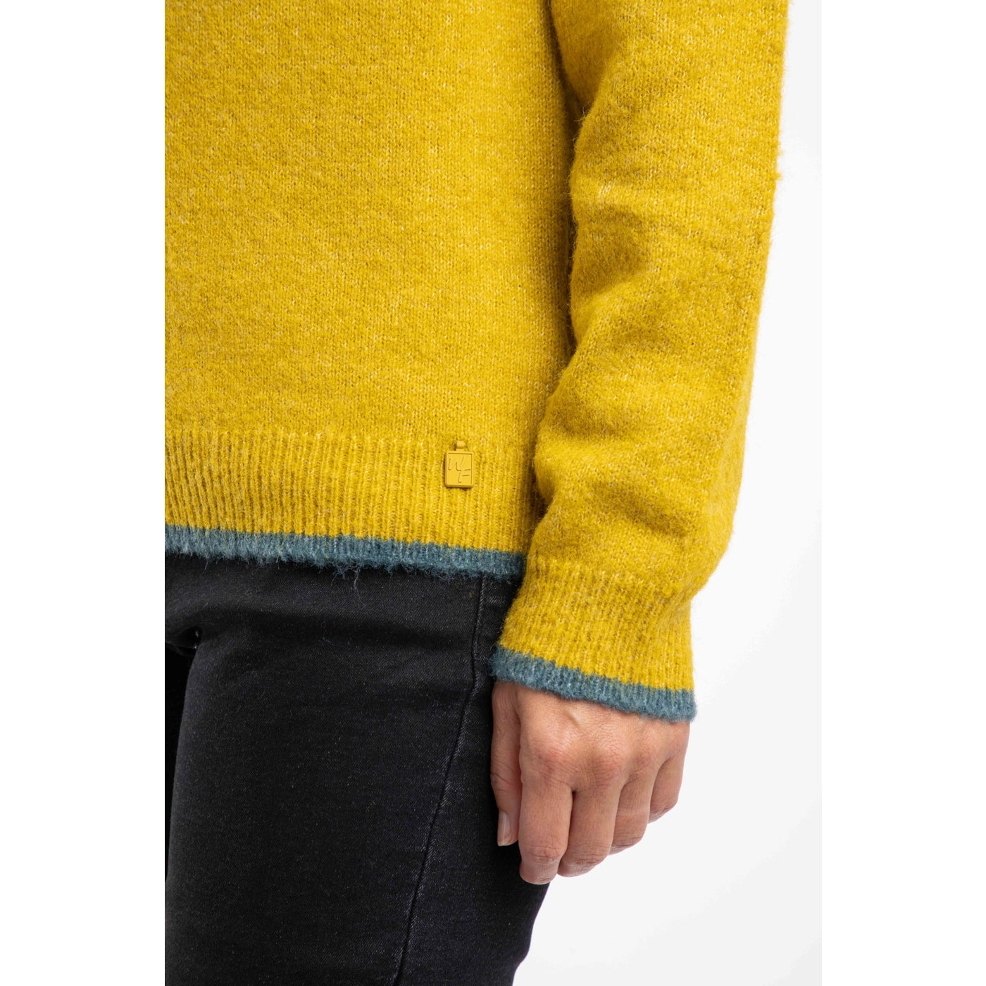 Close-up of a woman wearing a yellow Weird Fish Miska jumper with green trim on a white background