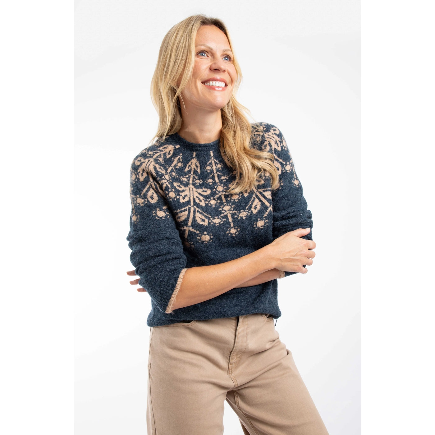 Woman wearing a navy Weird Fish Miska knitted jumper with a Fair Isle pattern with beige trousers on a white background