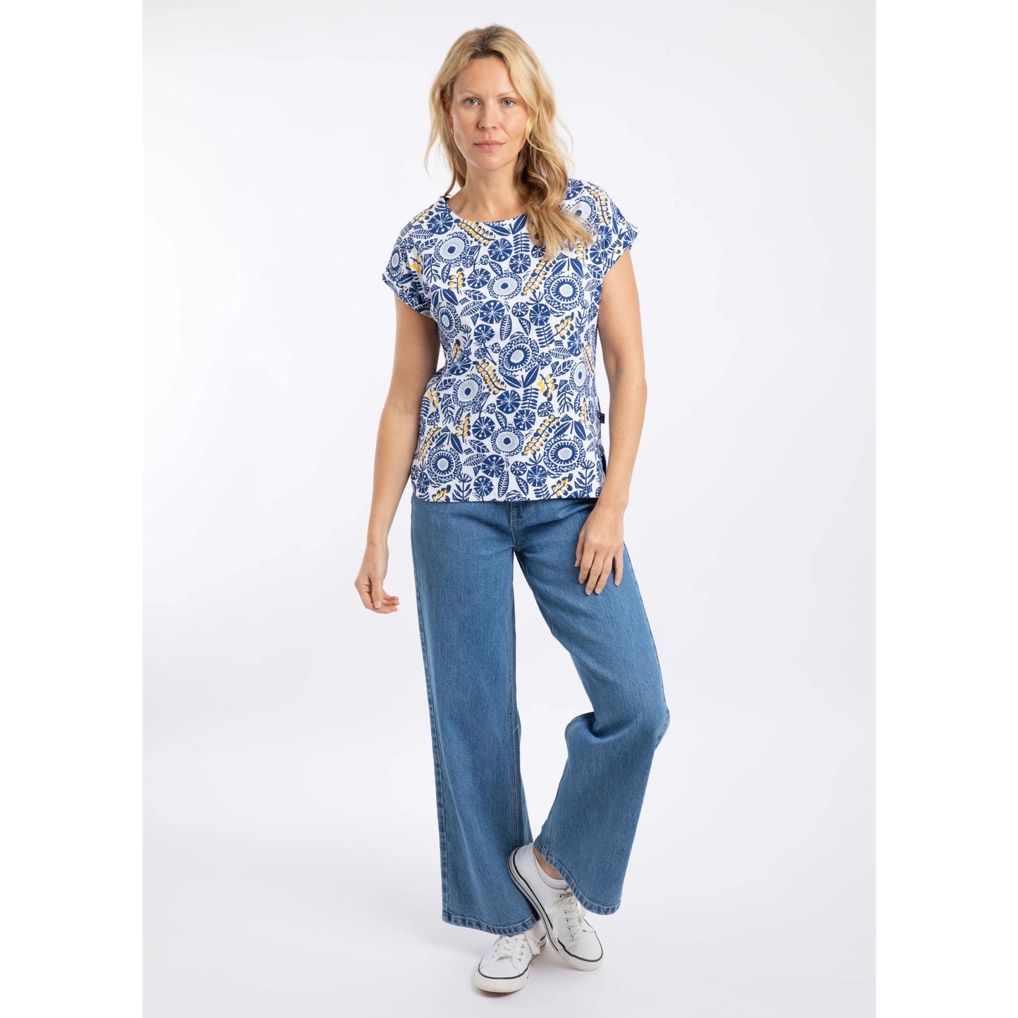 Woman wearing a blue and white floral Weird Fish Paw Paw short sleeve tee and jeans on a white background