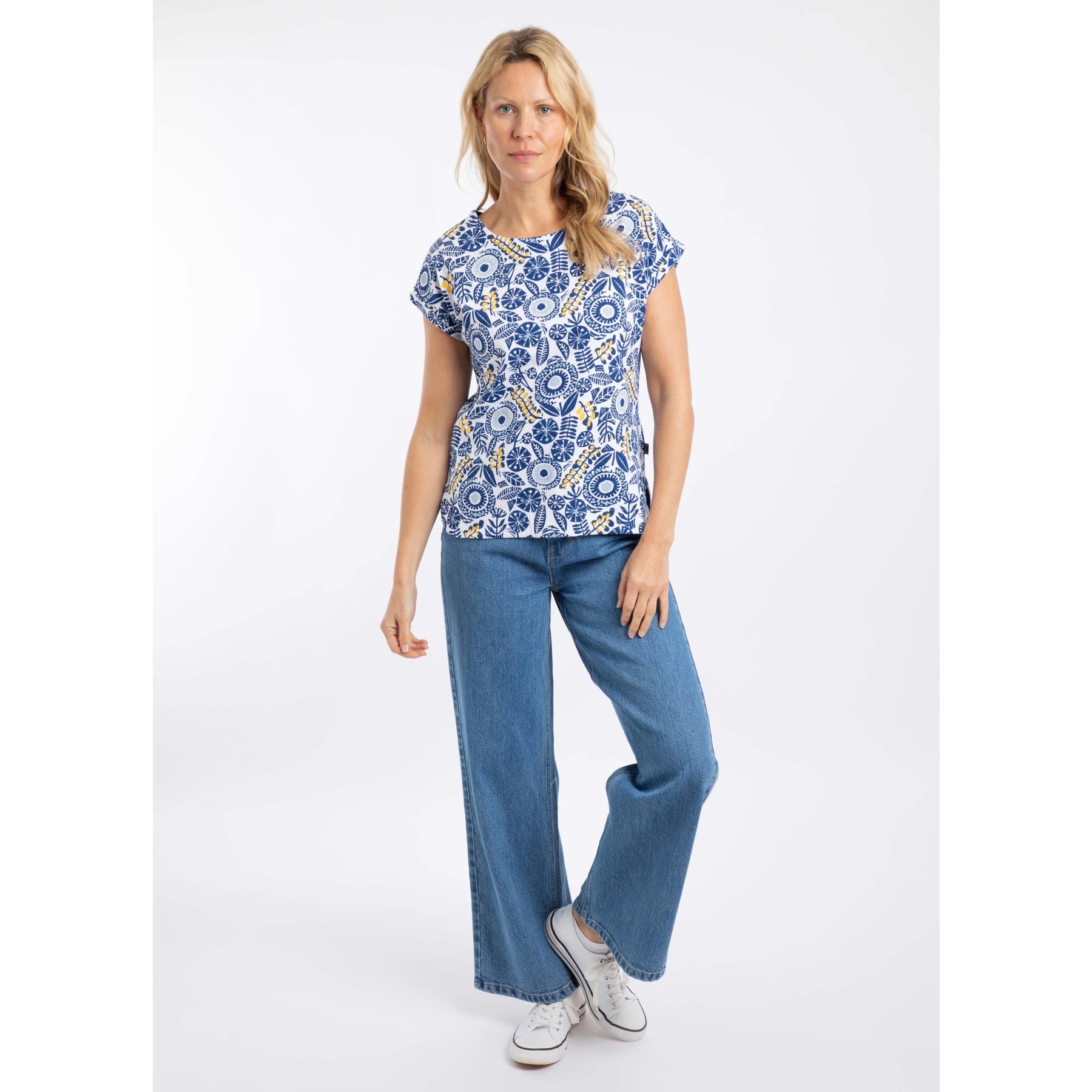 Woman wearing a blue and white floral Weird Fish Paw Paw short sleeve tee and jeans on a white background