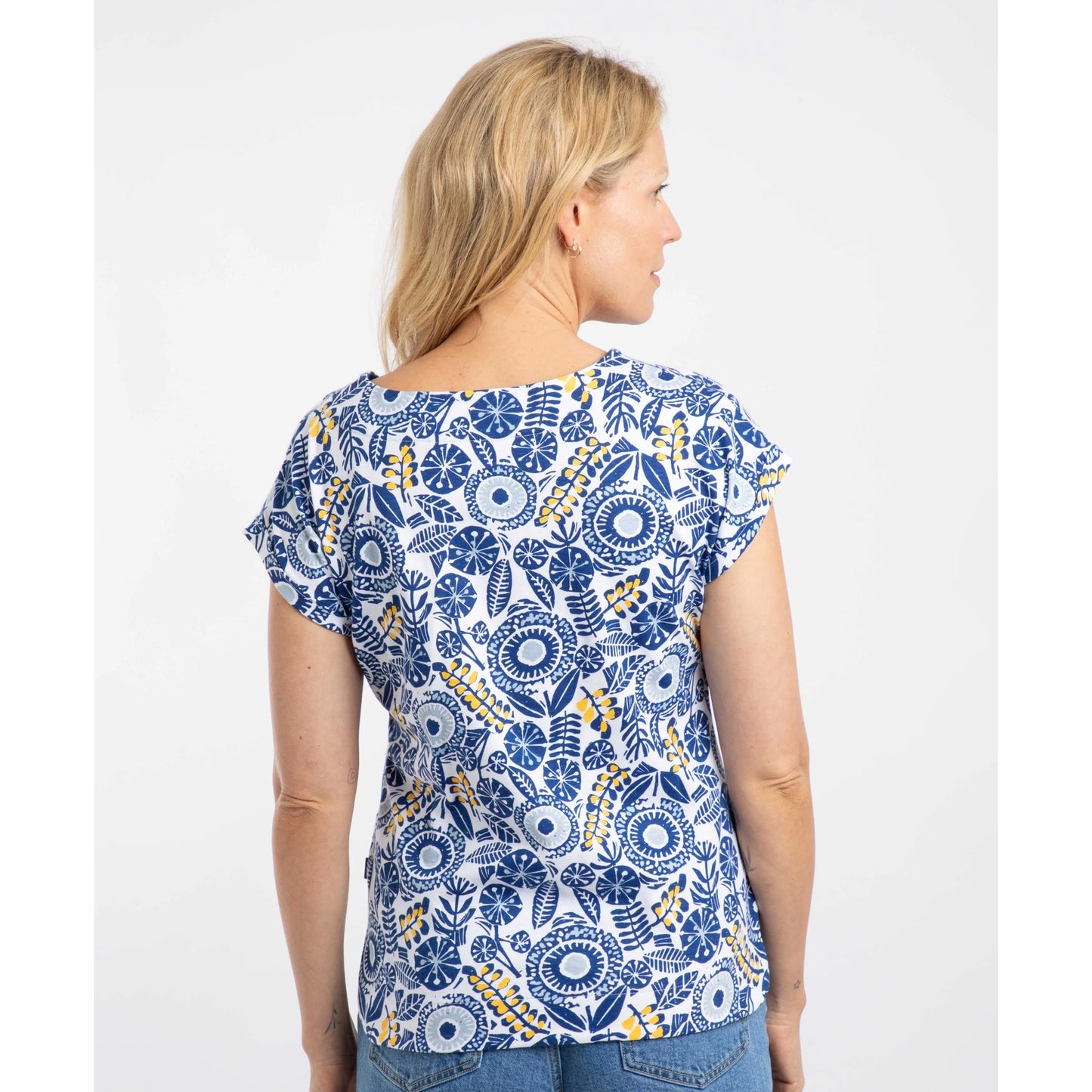 Back view of a woman wearing a Weird Fish blue floral patterned Paw Paw t-shirt on a white background