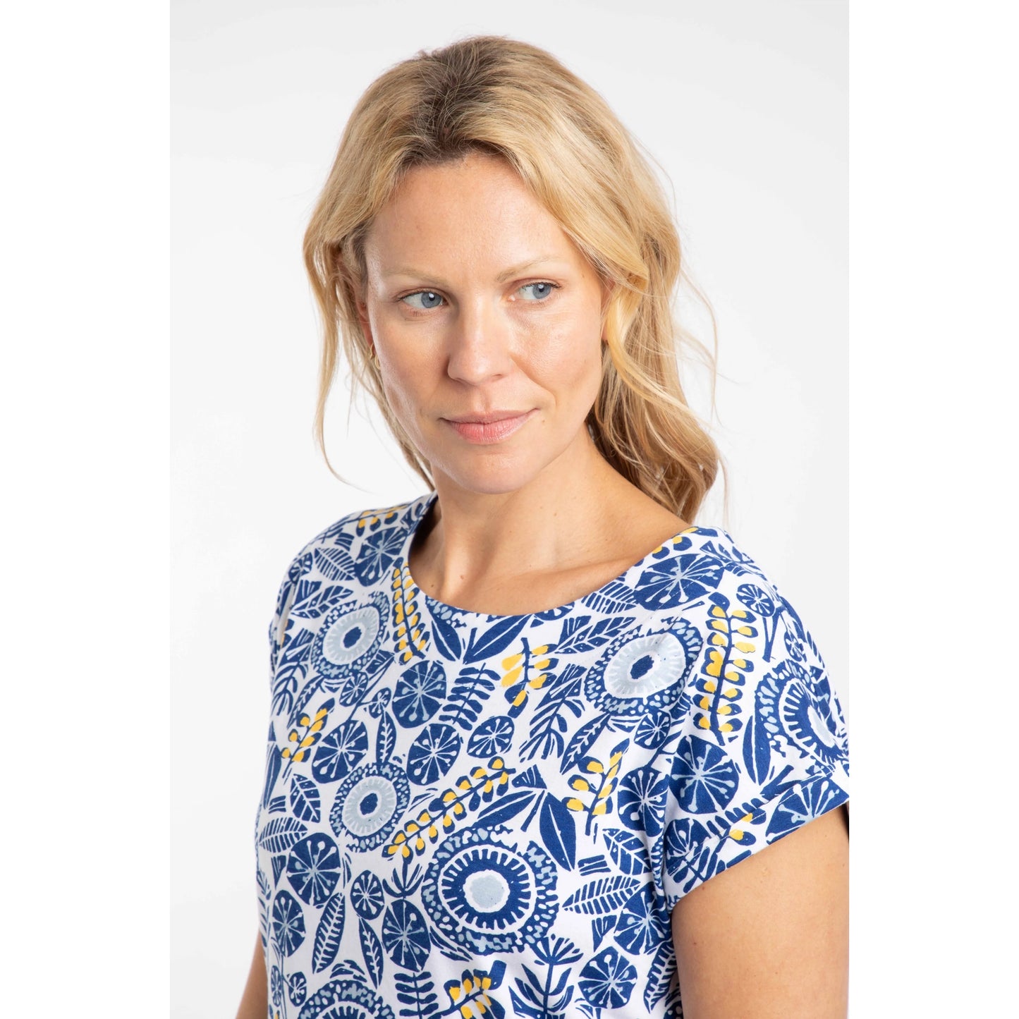Woman wearing a Weird Fish blue and white floral patterned short sleeve Paw Paw t-shirt on a white background