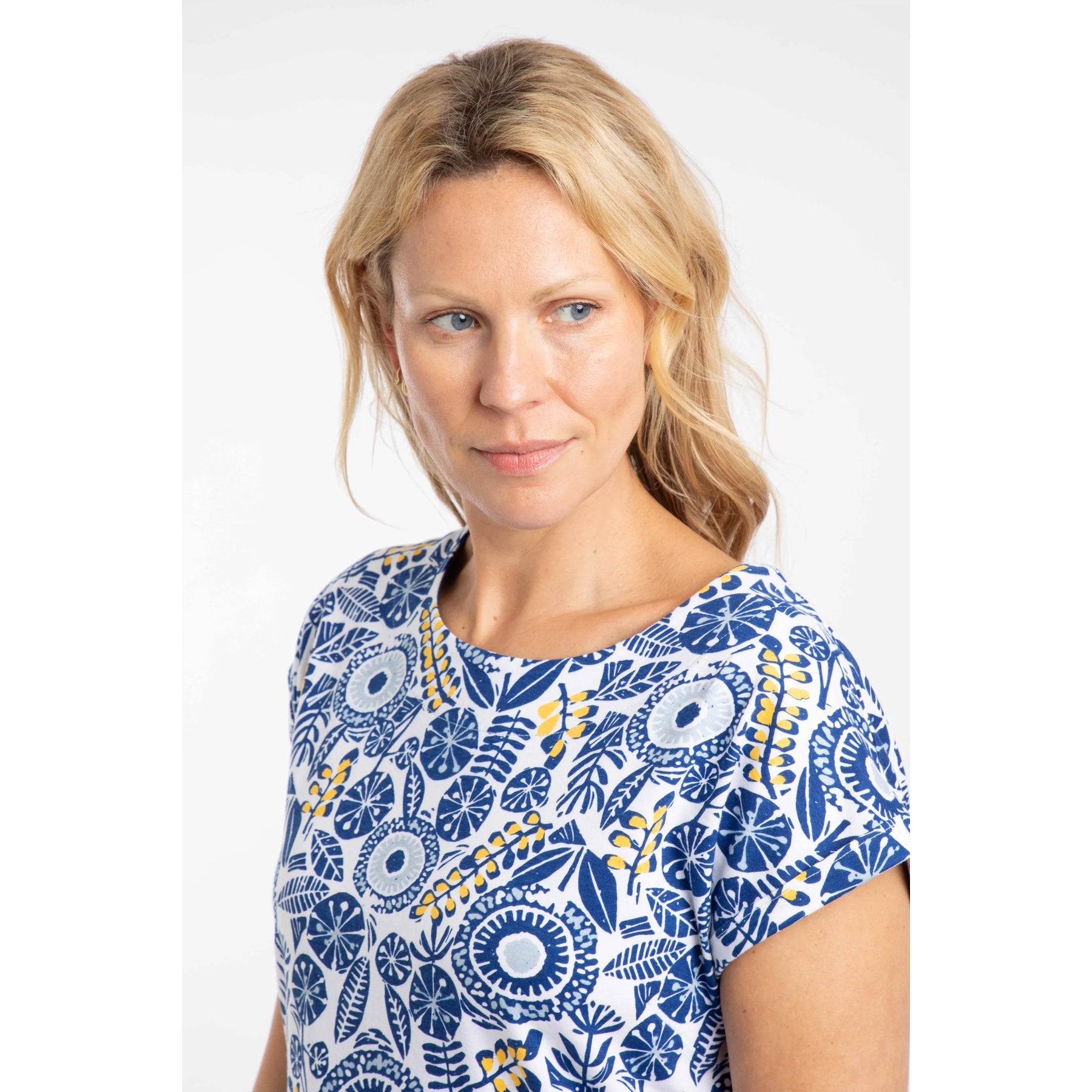 Woman wearing a Weird Fish blue and white floral patterned short sleeve Paw Paw t-shirt on a white background