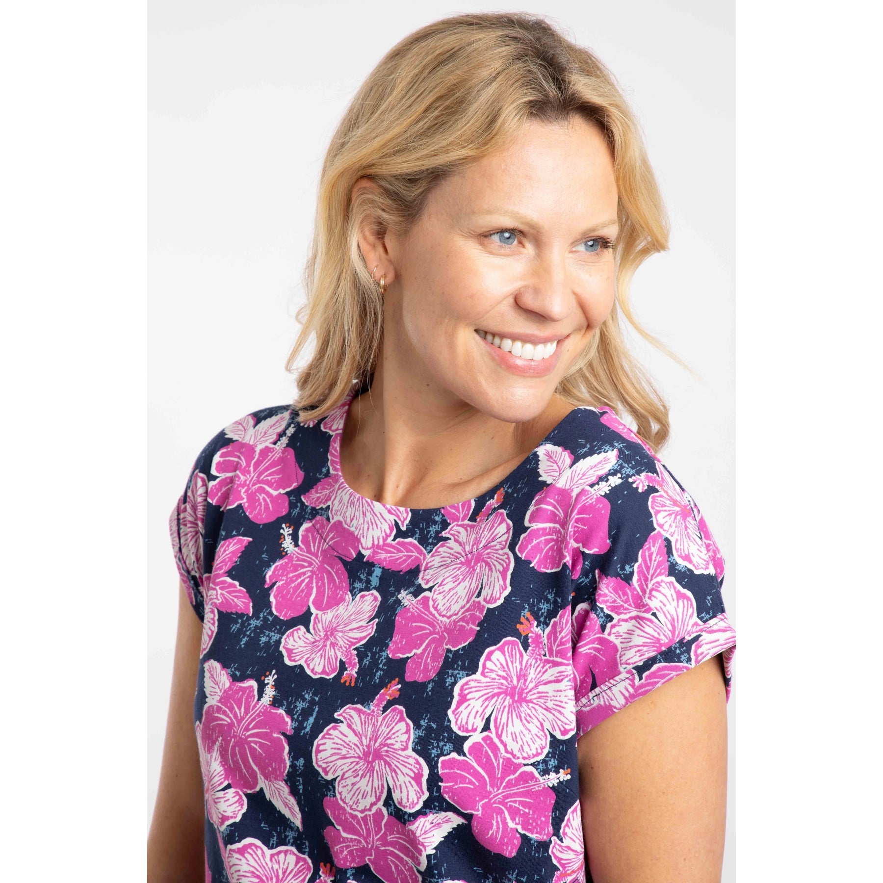 Close-up of a woman wearing a Weird Fish short sleeve Paw Paw t-shirt with a navy and pink floral pattern on a white background