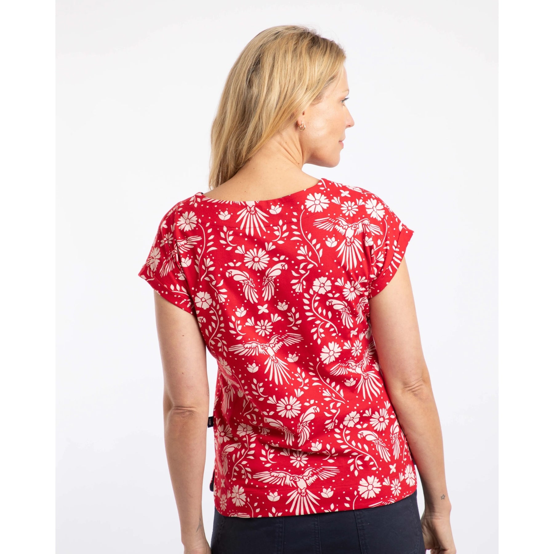 Back view of a woman wearing a red Weird Fish short sleeve Paw Paw t-shirt with a white floral and parrot print on a white background