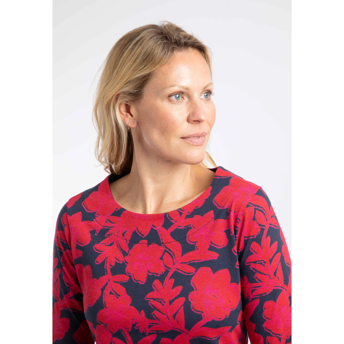 Close-up view of a woman wearing a Weird Fish three-quarter sleeve Pinto t-shirt in Cranberry Red with a bold floral pattern.