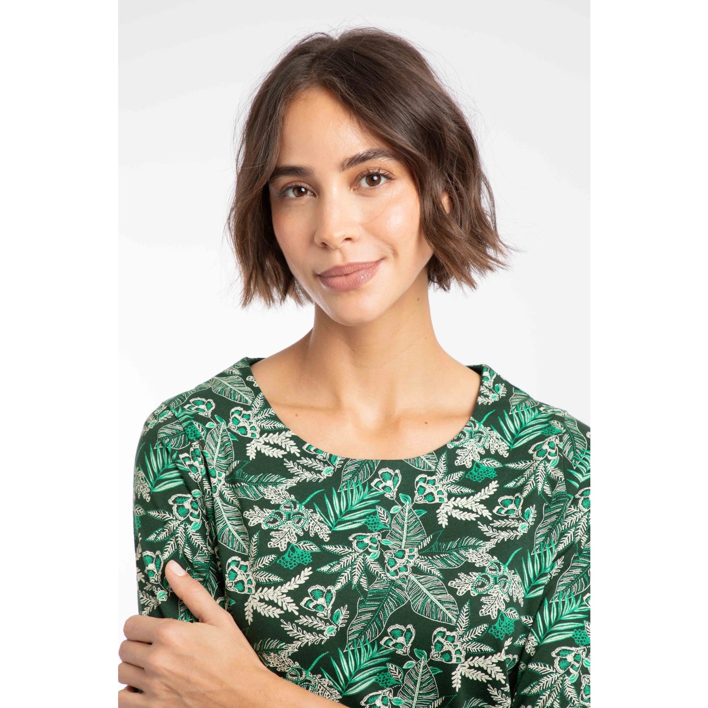 Close-up view of a woman wearing a Weird Fish three-quarter sleeve Pinto t-shirt in Laurel Green with a leafy floral pattern.