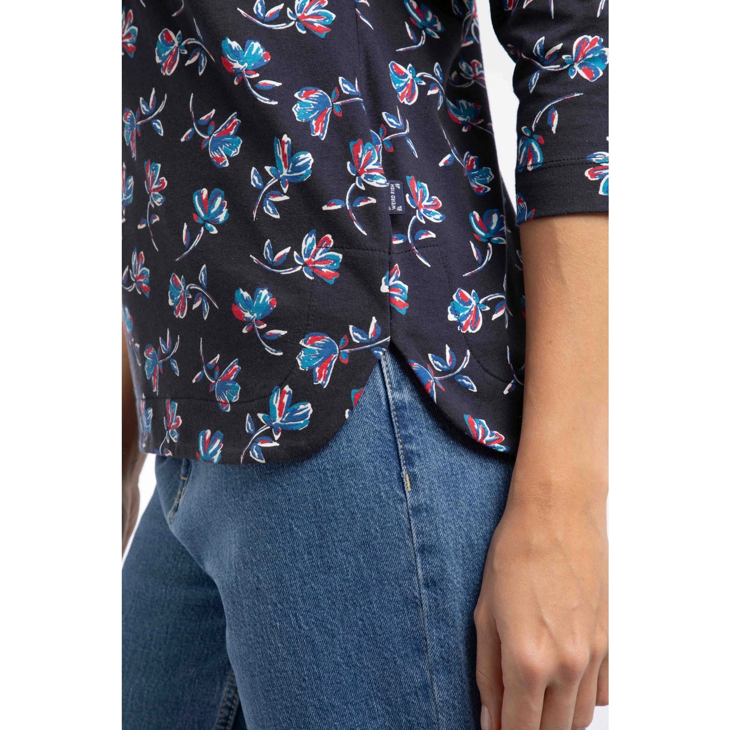 Close-up view of the curved side seam of a women's Weird Fish three-quarter sleeve Pinto t-shirt in Midnight navy with a blue and red floral pattern.