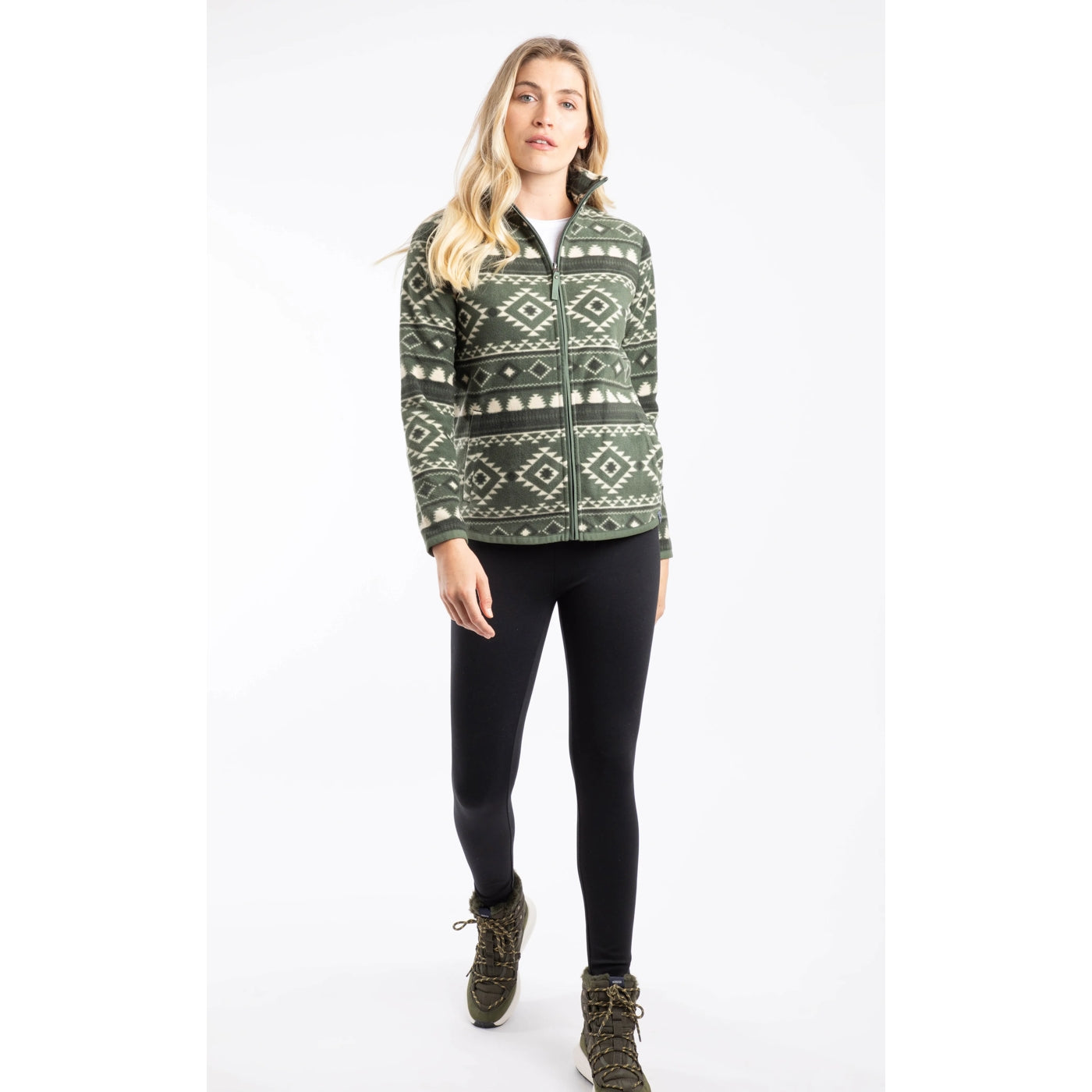 A woman wearing a Weird Fish full zip Rochelle fleece in Deep Lichen Green with an Aztec pattern with black leggings and boots.