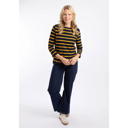 A woman wearing a Weird Fish Saffira 3/4 length sleeve top in Midnight Navy with Gold Yellow stripes with dark blue jeans.