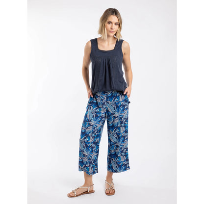 A woman wearing a pair of Weird Fish Sarita cropped trousers in indigo blue with a tropical leaf pattern.