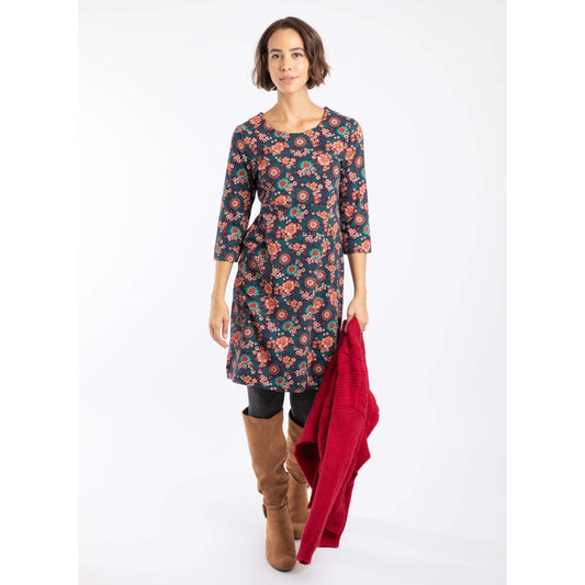 Woman wearing a Weird Fish dark blue and coral floral Starshine dress with a red jacket on a white background