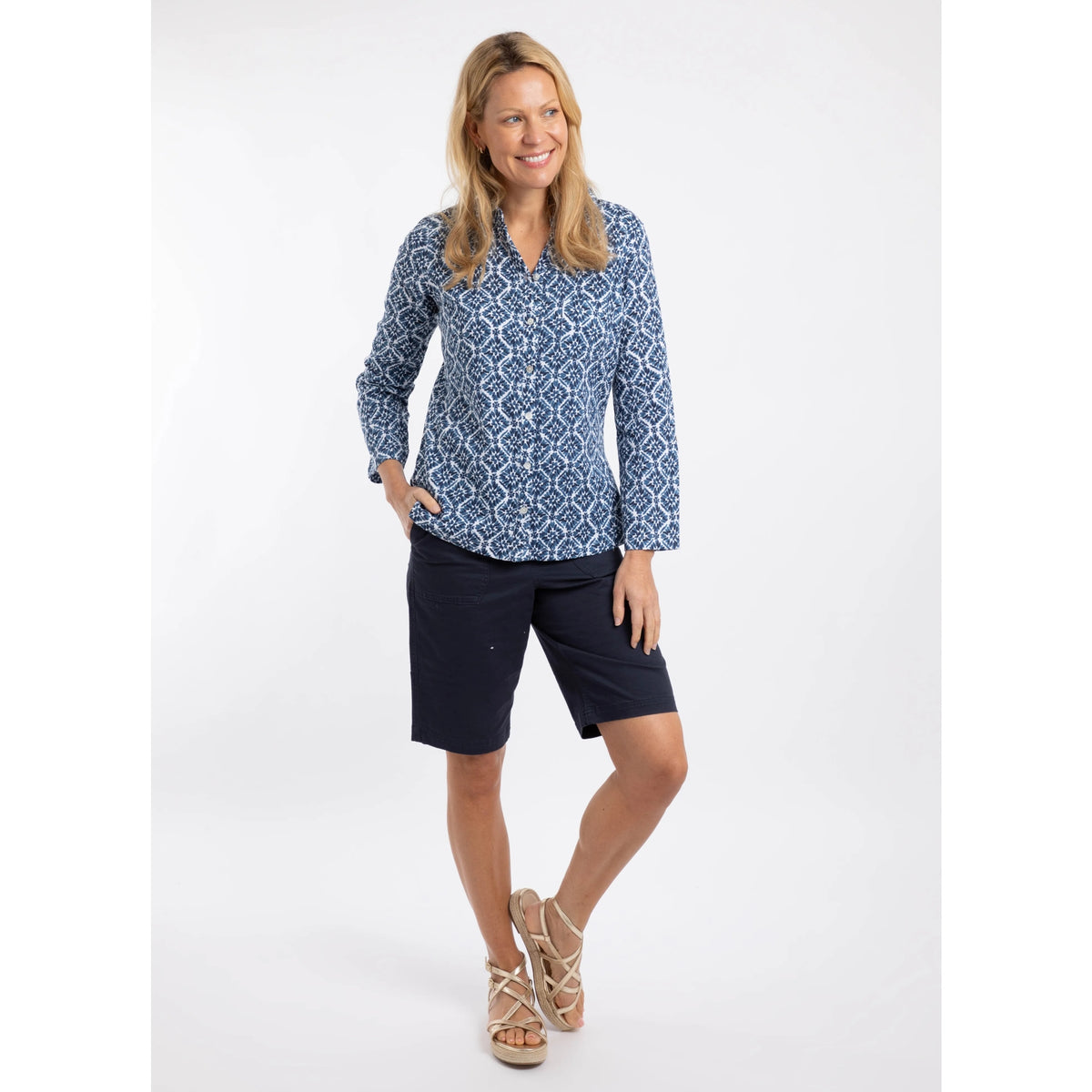Woman wearing a Weird Fish Syona blue patterned shirt and black shorts on a white background