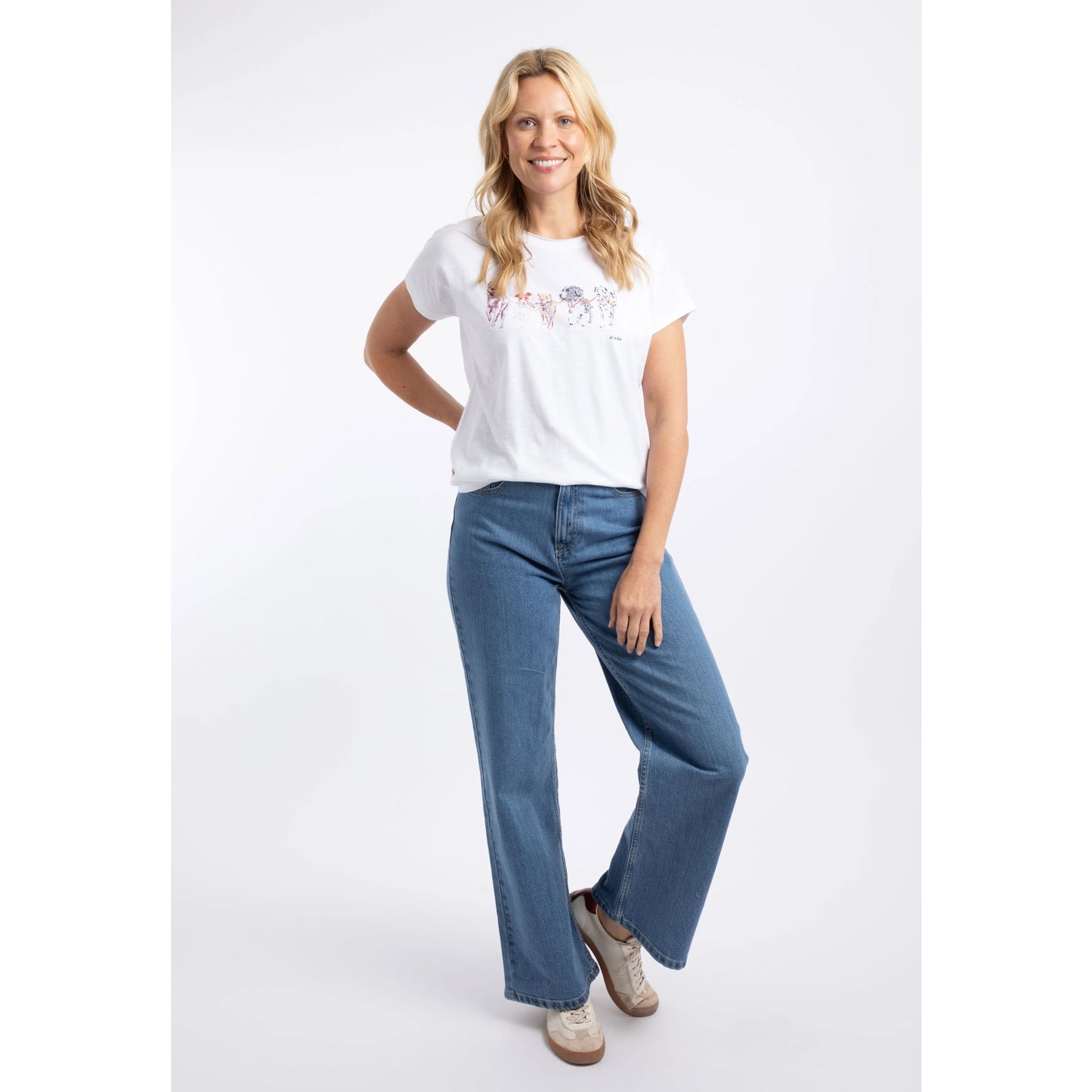 A woman wearing a Weird Fish short sleeve Take the Lead t-shirt in white with five dogs printed across the chest paired with blue jeans.