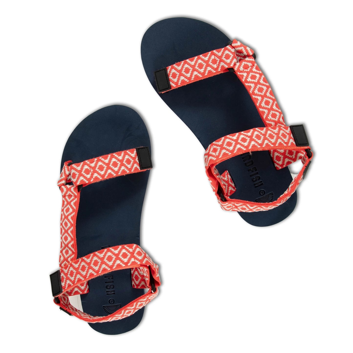 Top view of a pair of womens Weird Fish Trek webbing velcro strap sandals in coral with an Aztec style pattern and navy soles.