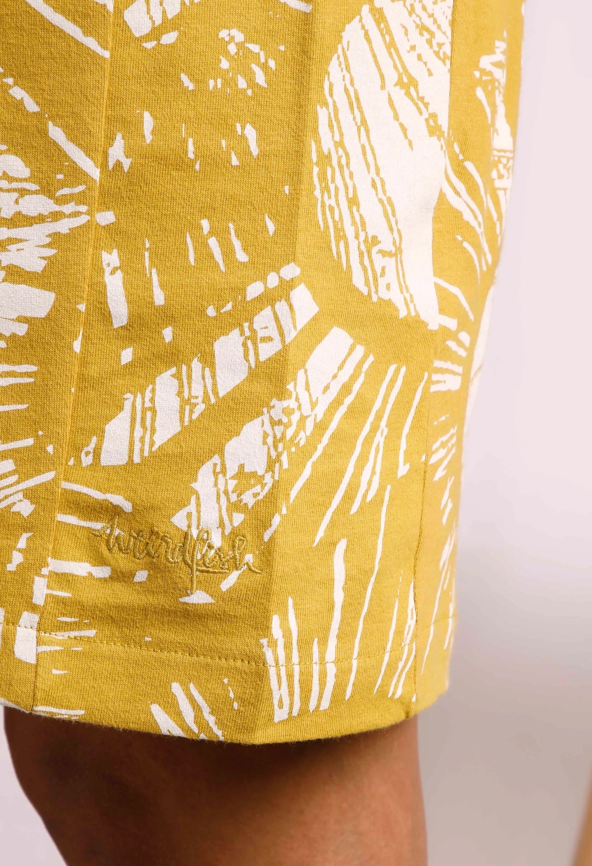 Weird Fish women's Adena dress in Warm Olive with a bold floral pattern and logo embroidered by the hem.